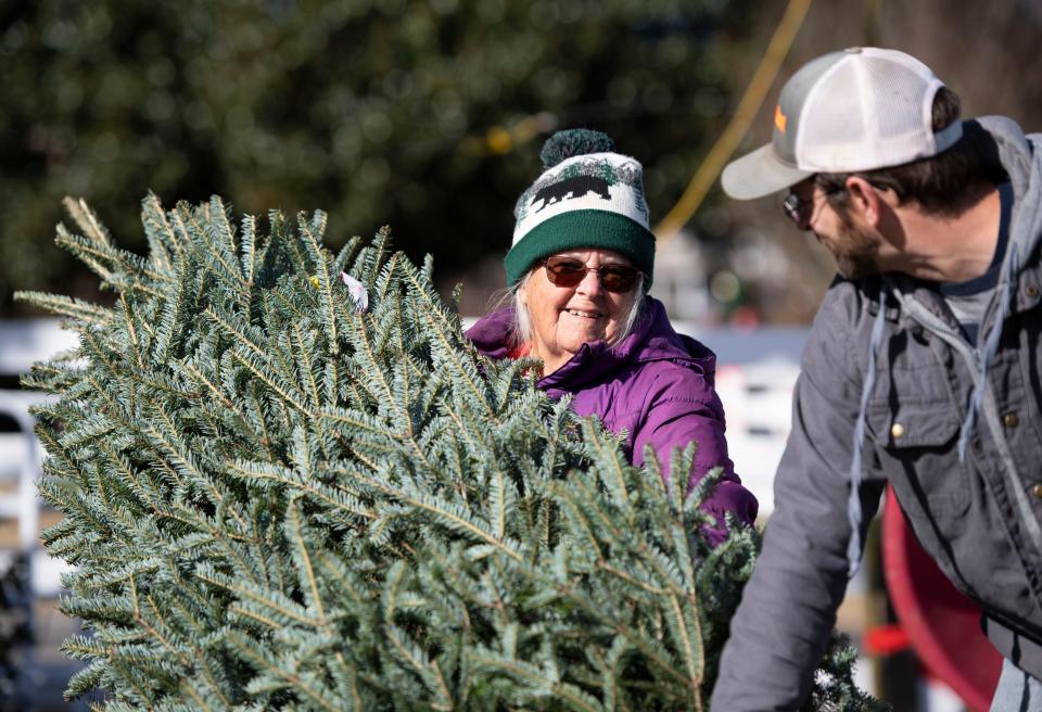 Part owner of Mystic farm, Susan Fink helps a customer shake their tree before purchasing at Mystic Farm, in Greenville, ,Monday, November 30, 2021. 