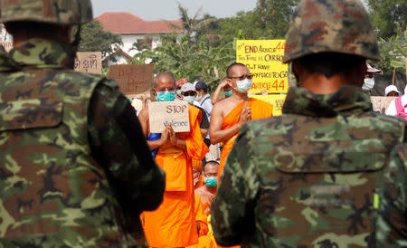 Buddhist monks pray and hold placards while soldiers stand guard at Dhammakaya temple, in Pathum Thani province, Thailand February 23, 2017. REUTERS/Chaiwat Subprasom