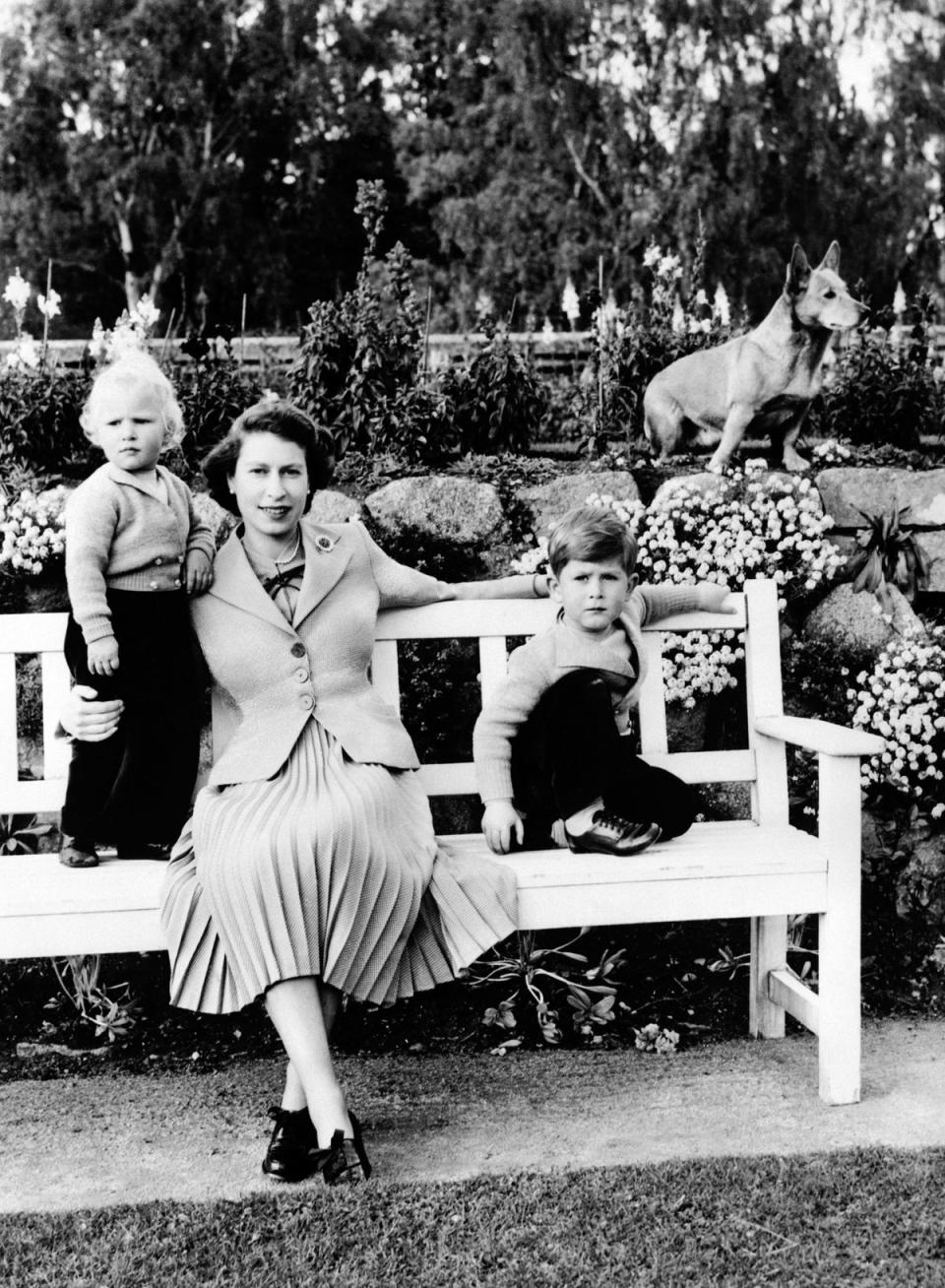 Queen Elizabeth II with Prince Charles and Princess Anne on a garden bench with the Queen's corgi, Sue, in Balmoral, Scotland. (PA)