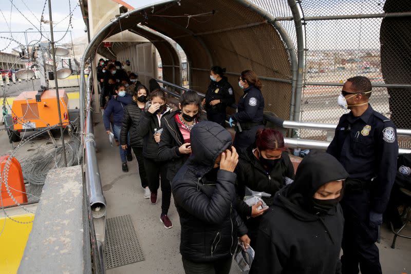 FILE PHOTO: Migrants deported from the U.S. walk towards Mexico at the Paso del Norte International border bridge, in this picture taken from Ciudad Juarez