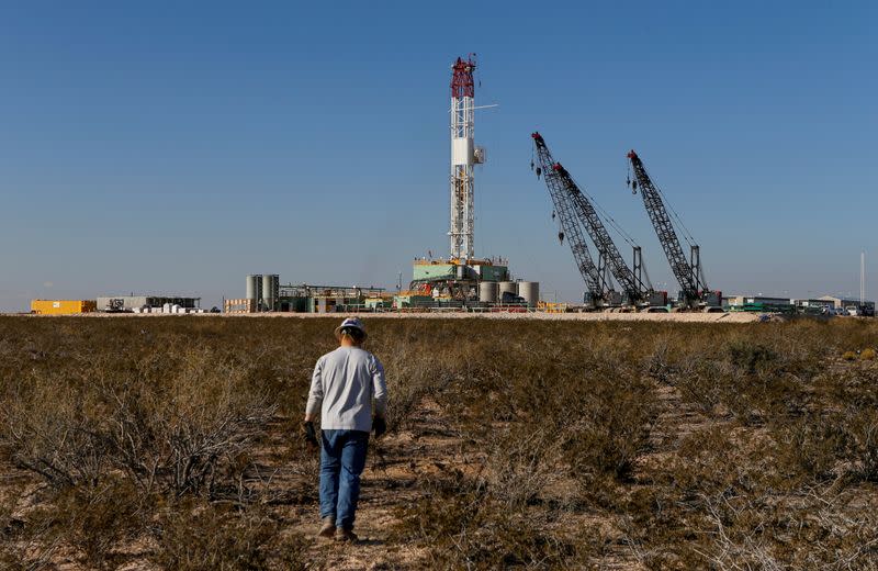 FILE PHOTO: An oil worker walks towards a drill rig in Loving County, Texas