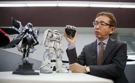 Shiro Nakamura, Senior Vice President and Chief Creative Officer of Nissan Motor Co, holds a model of Nissan Skyline GT-R supercar as he speaks to Reuters next to a model of "Zaku" character (C) from Japan's popular robot animation series Gundam, at the company's Global Design Center in Atsugi, Japan, April 14, 2016. REUTERS/Toru Hanai