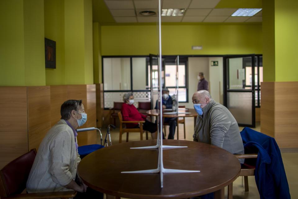 Residents meet with their families through a glass to protect themselves against COVID-19 at DomusVi nursing home in Leganes, Spain, Wednesday, March 10, 2021. Spain is preparing to tighten some pandemic restrictions on movement during the approaching Easter holiday, which is a traditional period for family visits. (AP Photo/Manu Fernandez)