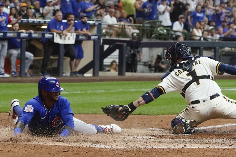 Chicago Cubs' Nelson Velazquez slides safely past Milwaukee Brewers catcher Victor Caratini during the sixth inning of a baseball game Tuesday, July 5, 2022, in Milwaukee. Velazquez scored on a hit by Rafael Ortega. (AP Photo/Morry Gash)