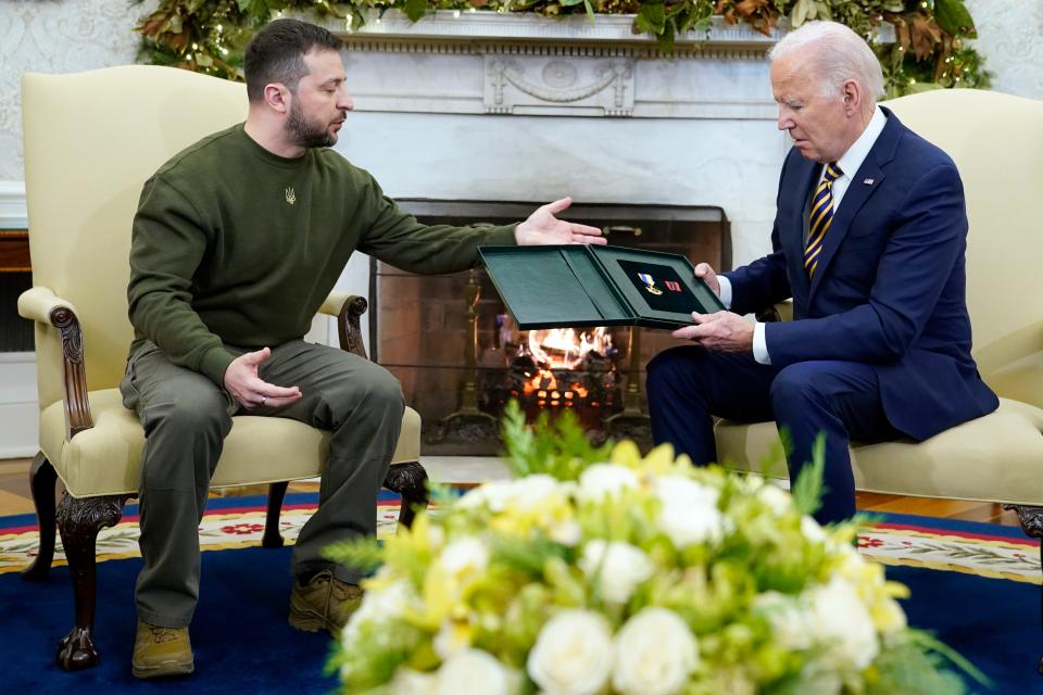 Ukrainian President Volodymyr Zelenskyy gesturing toward President Joe Biden after giving him a gift in the Oval Office.