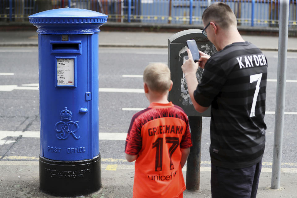 A man photographs a post box outside the Royal Victoria Hospital which has been painted blue in support of the National Health Service care workers, on the Falls Road in Belfast, Northern Ireland, Sunday April 26, 2020. The highly contagious COVID-19 coronavirus has impacted on nations around the globe, many imposing self isolation and exercising social distancing when people move from their homes. (Brian Lawless/ / PA via AP)