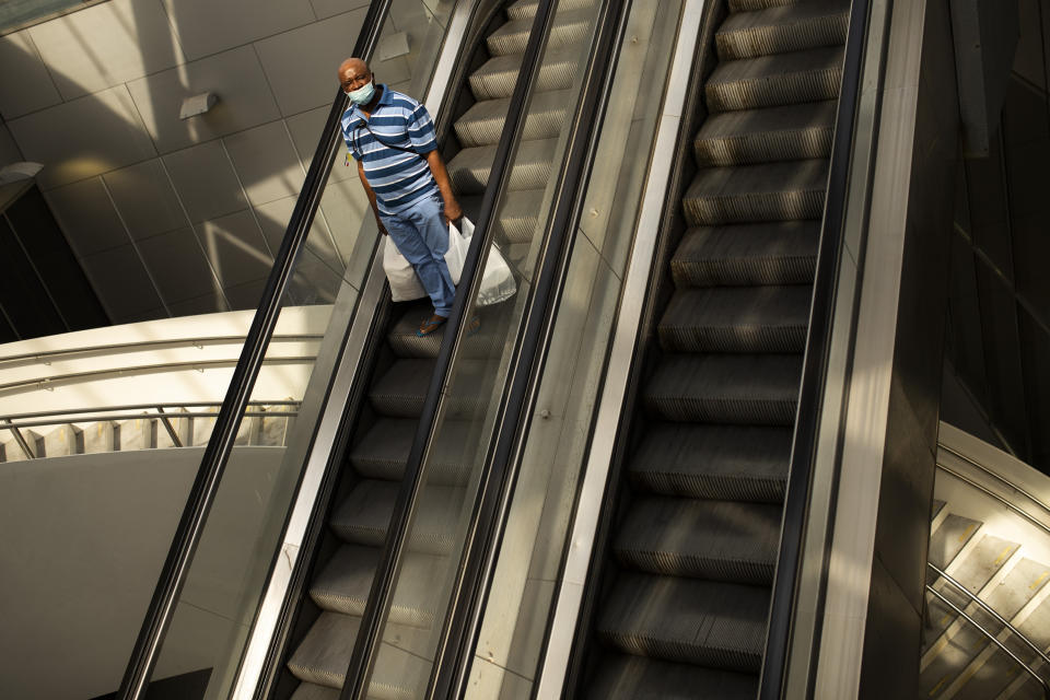 A man, wearing a mask to protect against the spread of coronavirus, stands on an escalator at Rogier metro station in Brussels, Monday, July 27, 2020. Belgian Prime Minister Sophie Wilmes unveiled Monday a new set of drastic social distancing measures aimed at avoiding a new general lockdown amid a surge of COVID-19 infections. (AP Photo/Francisco Seco)