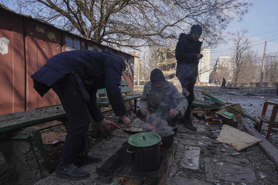 Men cook a meal in a street in Mariupol, Ukraine, Sunday, March 13, 2022. (AP Photo/Evgeniy Maloletka)