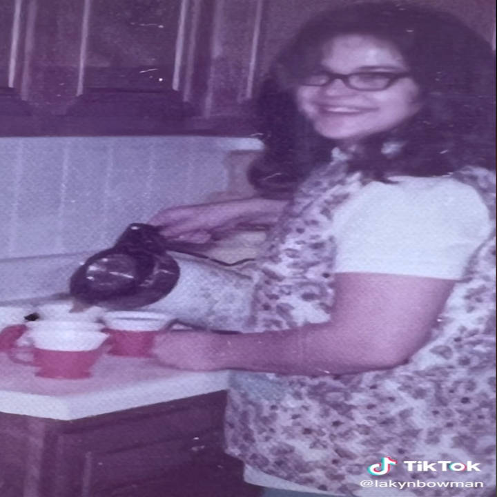 Lakyn's grandma smiles for the camera while pouring tea into cups in the kitchen