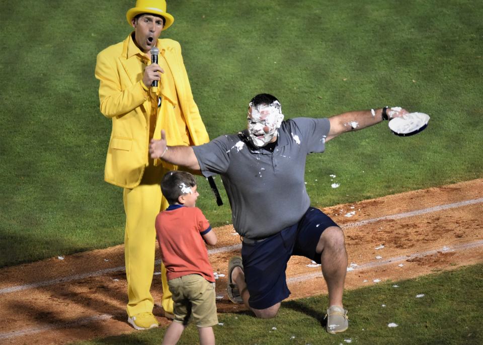 Savannah Bananas owner Jesse Cole, in a yellow tuxedo, narrates the action as a child delivers a pie to the face during the Bananas Premier Team's game against the Party Animals on March 27, 2021 at Hank Aaron Stadium in Mobile, Alabama.