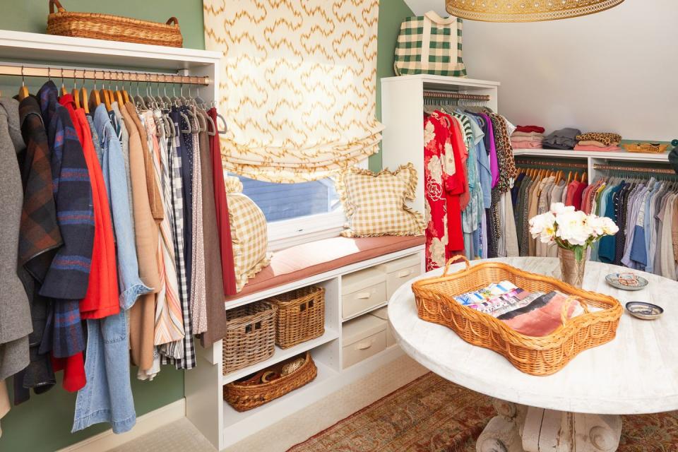 a closet with hanging racks and a window seat