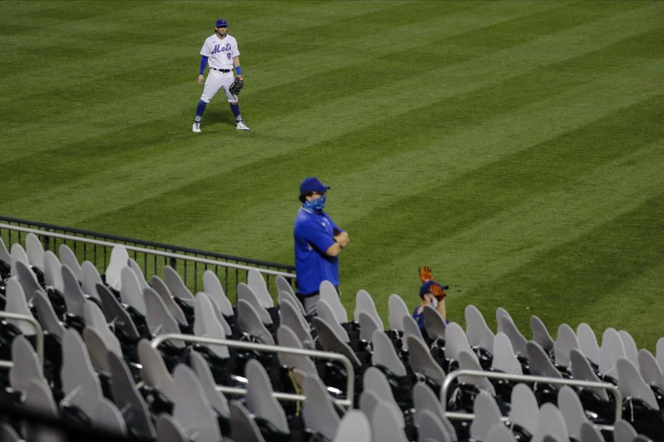 New York Mets left fielder Jeff McNeil looks at grounds crew members standing among cut-outs of fans during the second inning of a baseball game against the Miami Marlins Friday, Aug. 7, 2020, in New York. (AP Photo/Frank Franklin II)