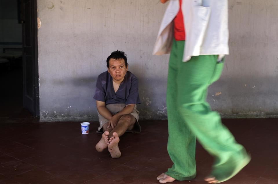 In this May 29, 2013 photo, a patient sits on the floor at the Neuro-Psychiatric Hospital in Asuncion, Paraguay. Doctors say most of the hospital's patients have been abandoned by their families. Many feel lucky to receive any kind of medical treatment, even if the system is broken. (AP Photo/Jorge Saenz)