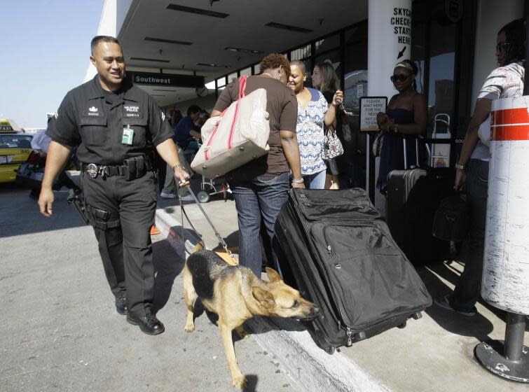 Los Angeles Police Officer Mark Sauvao and his K-9 partner Aya patrol a baggage check-in line Friday, Aug. 31, 2007, at Los Angeles International Airport, at the start of Labor Day holiday weekend in Los Angeles. (AP Photo/Nick Ut)