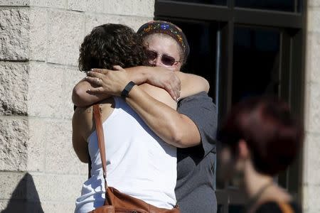 People hug as they gather at a meeting point for Umpqua Community College students to be bussed to pick up their cars, in Roseburg, Oregon, United States, October 2, 2015. REUTERS/Lucy Nicholson