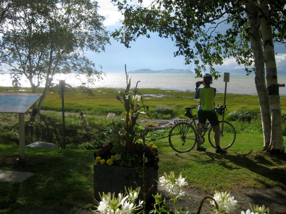FILE - A cyclist takes in the St. Lawrence vista at Notre-Dame-du-Portage, Quebec, on Aug. 12, 2015. Along the south shore of the St. Lawrence River in this area of around Kamouraska, the panorama of river, sky, flowers and gardens defines the magic of bicycling the Route Verte network in Quebec. (AP Photo/Cal Woodward, File)