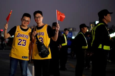 FILE PHOTO: Fans in LeBron James jerseys pose for pictures with Chinese flags near security personnel outside the Mercedes-Benz Arena before the NBA exhibition game between Brooklyn Nets and Los Angeles Lakers in Shanghai