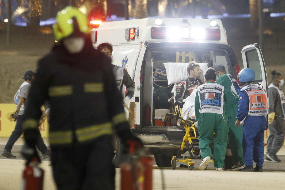 Haas driver Romain Grosjean of France is helped by medical staff after he crashed his car during the Formula One race in Bahrain International Circuit in Sakhir, Bahrain, Sunday, Nov. 29, 2020. (Hamad Mohammed, Pool via AP)