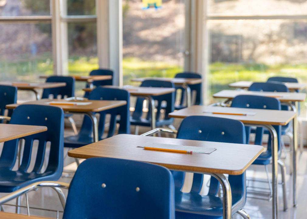 An empty classroom with small blue chairs at desks.