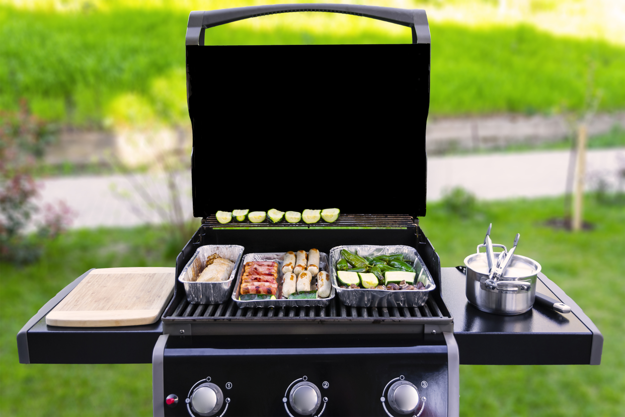 Backyard Gas Grill Loaded with Foil Trays of Food