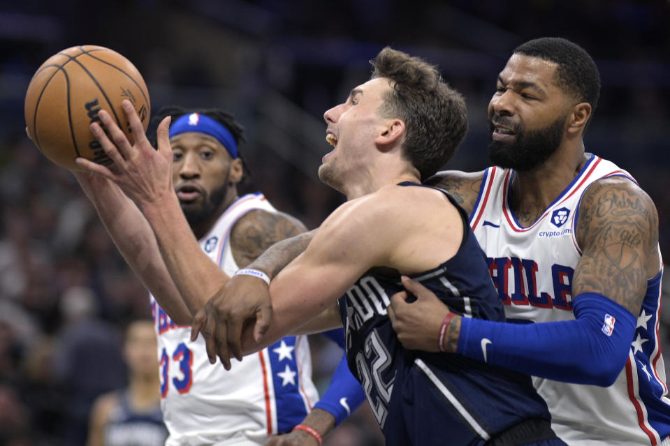 Orlando Magic forward Franz Wagner (22) is fouled by Philadelphia 76ers forward Marcus Morris Sr., right, while going up for a shot during the second half of an NBA basketball game, Wednesday, Dec. 27, 2023, in Orlando, Fla. (AP Photo/Phelan M. Ebenhack)