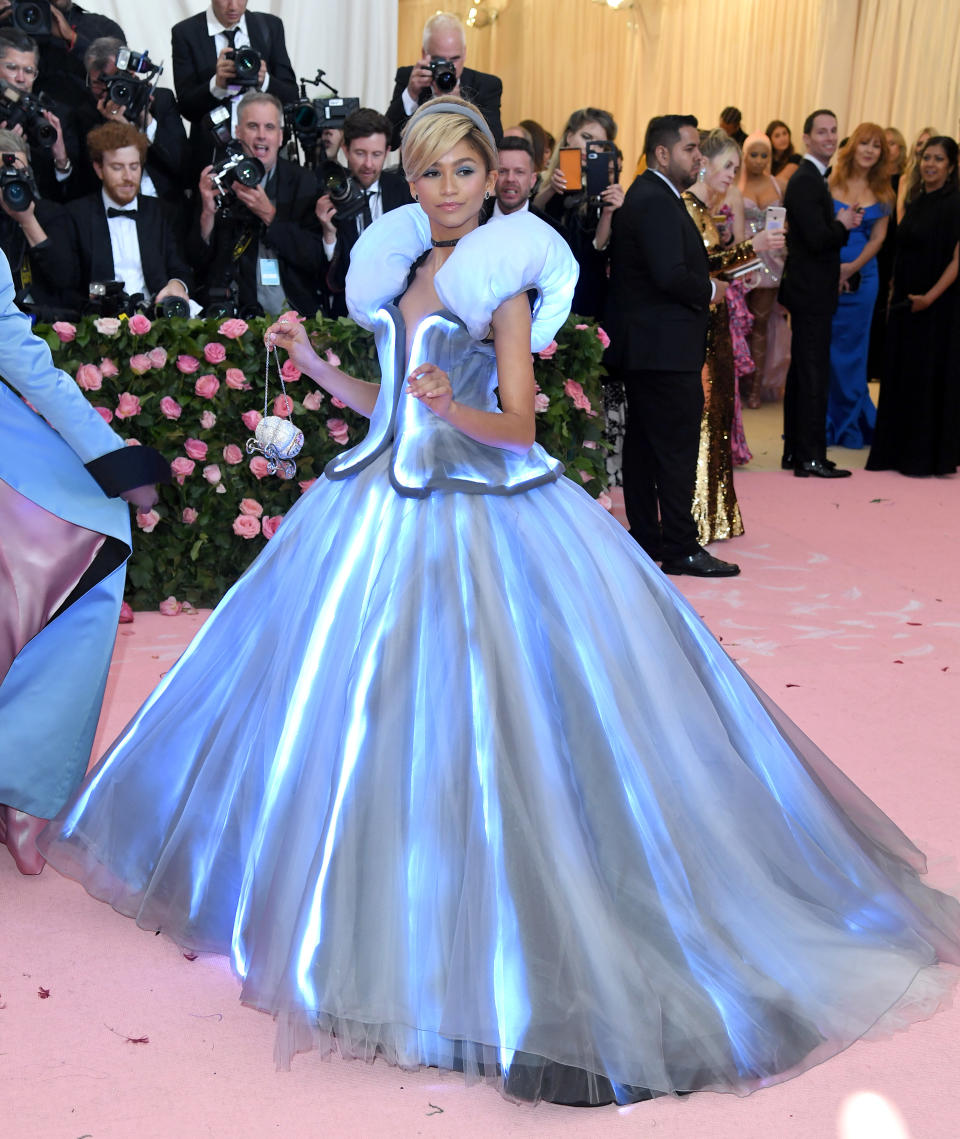 Elsa from Frozen in a live-action setting wearing a futuristic gown with structural shoulders and a luminescent skirt