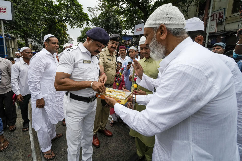 FILE - Muslims offer sweets to police officers on duty after offering prayers on Eid al-Fitr in Kolkata, India, Tuesday, May 3, 2022. Muslims are the largest minority group in the Hindu-majority nation. (AP Photo/Bikas Das, File)