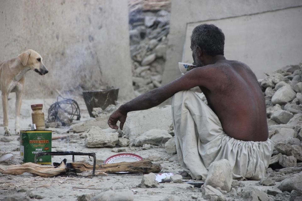 A survivor of an earthquake sits as he takes tea on the rubble of a mud house after it collapsed following the quake in the town of Awaran, southwestern Pakistani province of Baluchistan, September 25, 2013. The death toll from a powerful earthquake in Pakistan rose to at least 208 on Wednesday after hundreds of mud houses collapsed on people in a remote area near the Iranian border, officials said. (REUTERS/Sallah Jan)