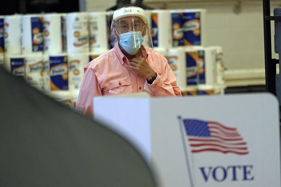 Harris County election clerk Jose Mendoza watches over voting booths, Monday, June 29, 2020, in Houston. Early voting for the Texas primary runoffs began Monday. (AP Photo/David J. Phillip)