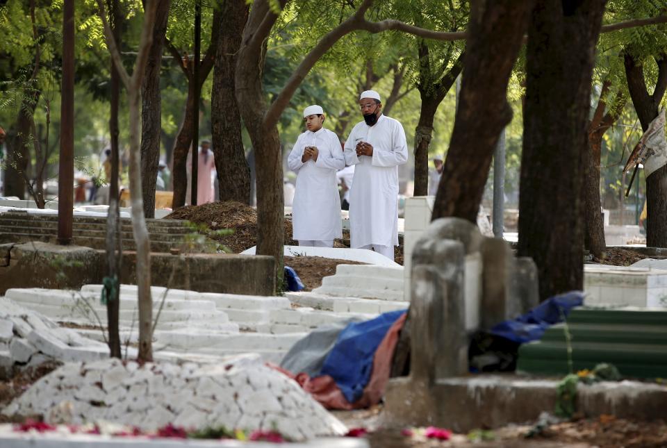 Muslims offer prayers next to the graves of their relatives on the occasion of Eid-ul-Fitr, at a graveyard in Ahmedabad, Friday, May 14, 2021.