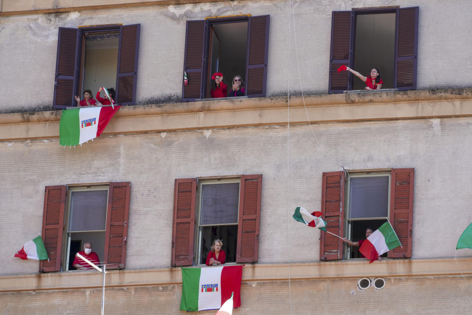 People wave and chant from their windows with the Italian flags draped on the occasion of the 75th anniversary of Italy's Liberation Day, in Rome, Saturday, April 25, 2020. Italy's annual commemoration of its liberation from Nazi occupation is celebrated on April 25 but lockdown measures in the coronavirus-afflicted country mean no marches can be held this year and the National Association of Italian Partisans has invited all to sing “Bella Ciao", the anthem of Italy’s communist resistance, from their windows. (AP Photo/Andrew Medichini)