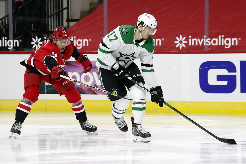 Dallas Stars' Nick Caamano (17) moves the puck as he is pestered by Carolina Hurricanes' Jake Bean (24) during the first period of an NHL hockey game in Raleigh, N.C., Sunday, Jan. 31, 2021. (AP Photo/Karl B DeBlaker)
