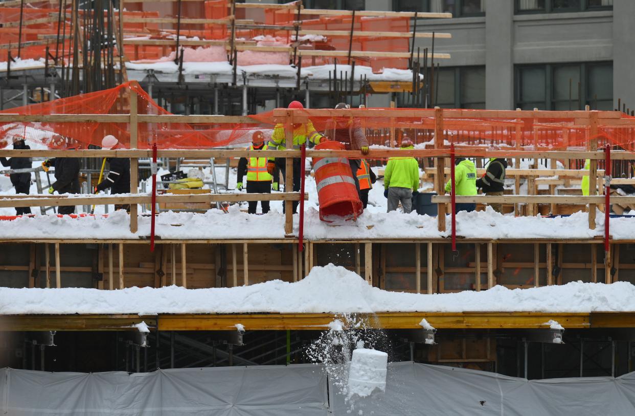 Construction workers free a building construction site of snow in the Brooklyn Borough of New York on February 2, 2021. - A huge snowstorm has brought chaos to the United States' east coast, shuttering airports, closing schools and forcing the postponement of coronavirus vaccinations into Tuesday morning as New York City steeled itself for possibly one of its heaviest ever snowfalls. New York declared a state of emergency restricting non-essential travel, moved all children back to remote learning and rescheduled long-awaited vaccine shots as some parts of the city were hit by more than 18 inches (1.5 feet) of snow. CNN meteorologists said that figure could reach two feet before the storm comes to an end. (Photo by Angela Weiss / AFP) (Photo by ANGELA WEISS/AFP via Getty Images)