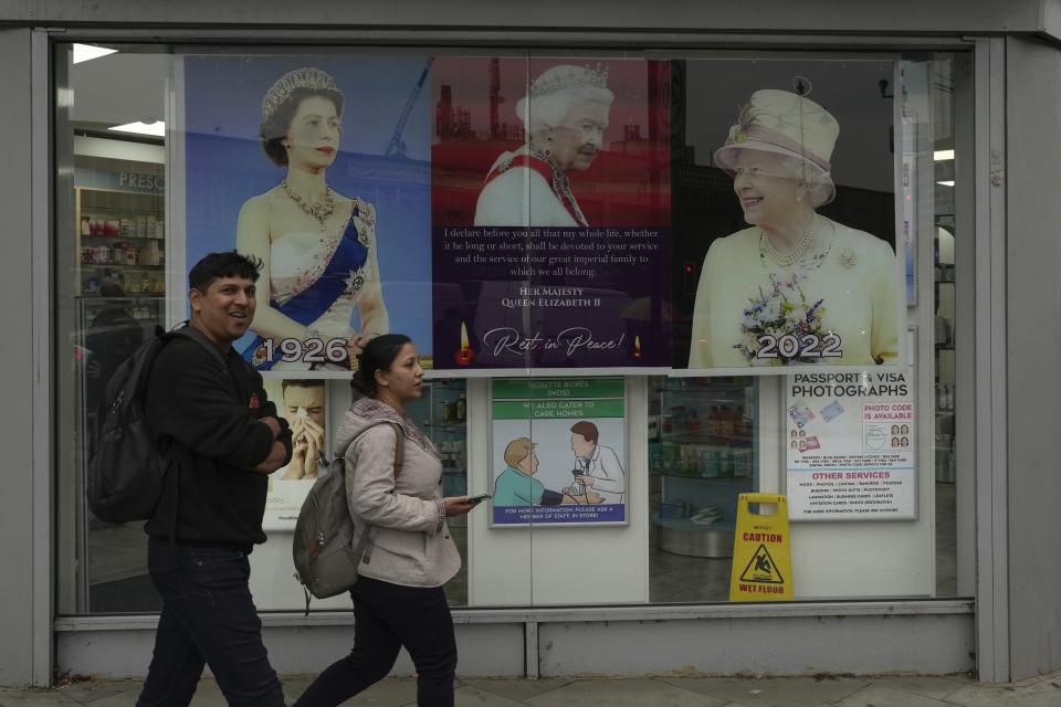Posters of Queen Elizabeth II are displayed outside a pharmacy in the district of Southall in London, Tuesday, Sept. 13, 2022. In a church in a West London district known locally as Little India, a book of condolence for Queen Elizabeth II lies open. Five days after the monarch’s passing, few have signed their names. The congregation of 300 is made up largely of the South Asian diaspora, like the majority of the estimated 70,000 people living in the district of Southall, a community tucked away in London's outer reaches of London and built on waves of migration that span 100 years. (AP Photo/Kin Cheung)