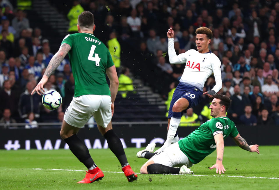 Dele Alli of Tottenham Hotspur shoots past Lewis Dunk and Shane Duffy of Brighton and Hove Albion during the Premier League match between Tottenham Hotspur and Brighton & Hove Albion.