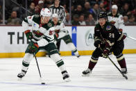 Minnesota Wild left wing Kirill Kaprizov (97) skates with the puck away from Arizona Coyotes center Barrett Hayton in the first period during an NHL hockey game, Monday, Feb. 6, 2023, in Tempe, Ariz. (AP Photo/Rick Scuteri)