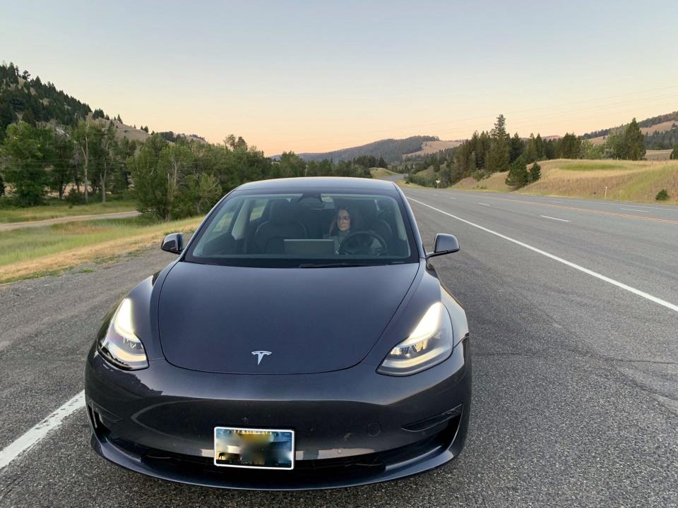 The author is seen in the front seat of a Tesla Model 3.