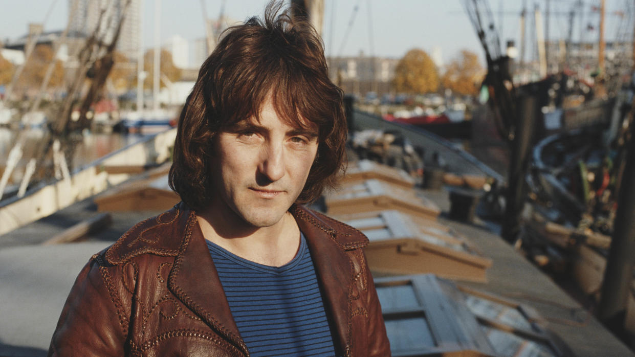  English singer-songwriter and former Wings and Moody Blues guitarist, Denny Laine posed wearing a leather jacket outside near an harbor 1981. 