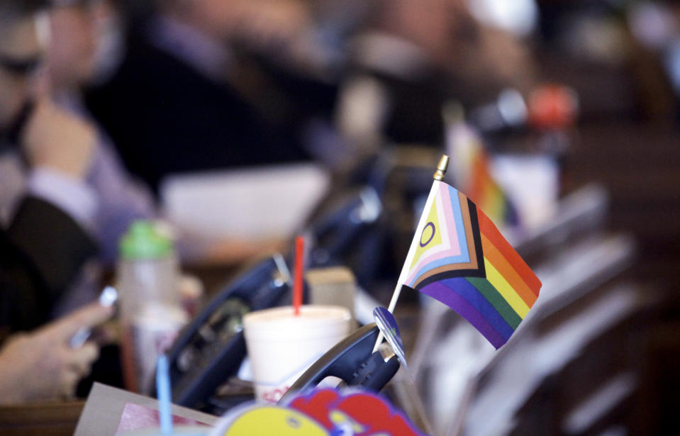 FILE - A flag supporting LGBTQ+ rights decorates a desk on the Democratic side of the Kansas House of Representatives during a debate, March 28, 2023, at the Statehouse in Topeka, Kan. On Friday, April 28, The Associated Press reported on stories circulating online incorrectly claiming a new law in Kansas, which bans transgender athletes from girls' and women's sports, authorizes genital inspections of children. (AP Photo/John Hanna, File)