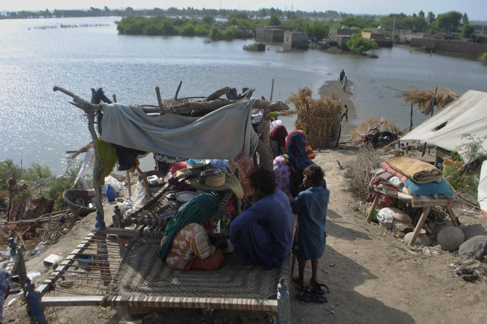 Displaced families who fled their flood-hit homes take refuge along a roadside in Jamshoro, southern Sindh province, Pakistan, Friday, Sept. 16, 2022. The devastating floods affected over 33 million people and displaced over half a million people who are still living in tents and make-shift homes. The water has destroyed 70% of wheat, cotton and other crops in Pakistan. (AP Photo/Pervez Masih)