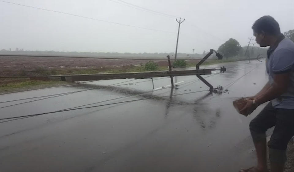 In this grab made from video provided by KK Productions, a man holds a brick to build a road diversion to help vehicles avoid an electric pole that fell after a cyclone struck Nagapattinam, in the southern Indian state of Tamil Nadu, Friday, Nov. 16, 2018. Cyclone Gaja hit the coast of southern India on Friday, killing more than 10 people and damaging homes after more than 80,000 residents were evacuated. (KK Production via AP)