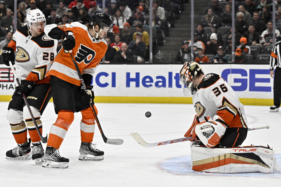 Anaheim Ducks goaltender John Gibson, right, blocks a shot with Philadelphia Flyers left wing Joel Farabee, center, and Ducks defenseman Nathan Beaulieu watching during the first period of an NHL hockey game in Anaheim, Calif., Monday, Jan. 2, 2023. (AP Photo/Alex Gallardo)