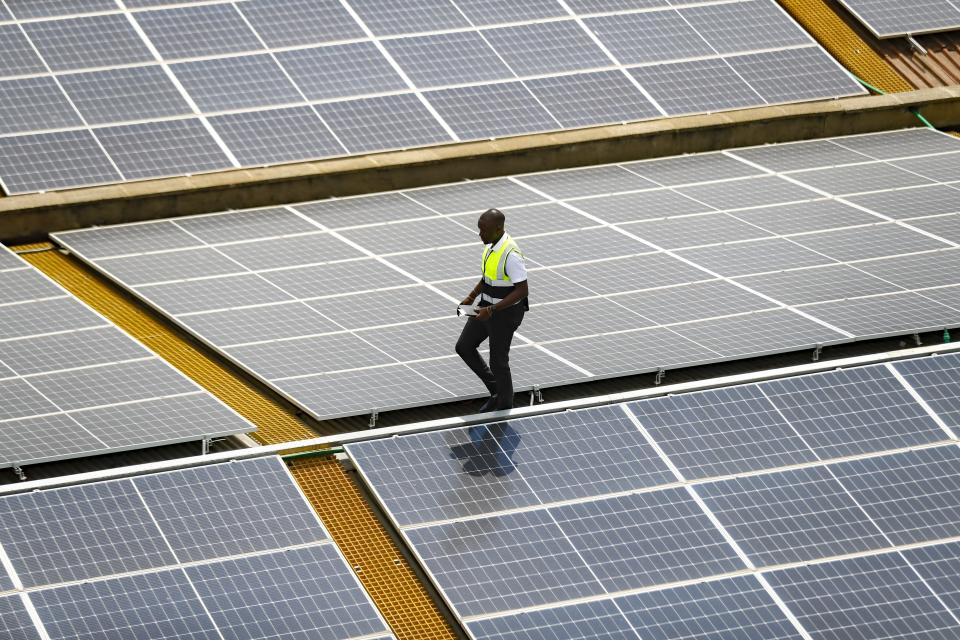 FILE - Mark Munyua, CP solar's technician, examines solar panels on the roof of a company in Nairobi, Kenya, Sept. 1, 2023. The IEA’s annual world energy outlook, which analyzes the global picture of energy supply and demand, was released Tuesday, Oct. 24. (AP Photo/Brian Inganga, File)