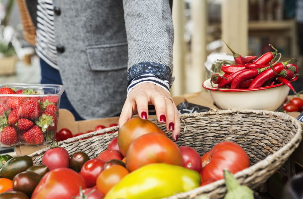 Close up of hand picking tomato from basket.