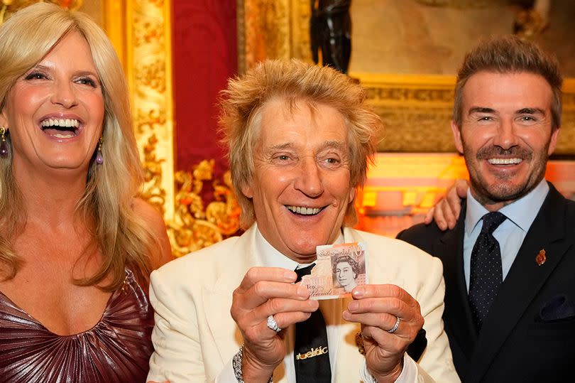 Rod Stewart holds a 10-pound note showing the face of the late Queen Elizabeth II as he jokes with a photographer, with Penny Lancaster (left) and David Beckham (right), as they attend the King's Foundation charity's inaugural awards at St James's Palace, London. Picture date: Tuesday June 11, 2024.