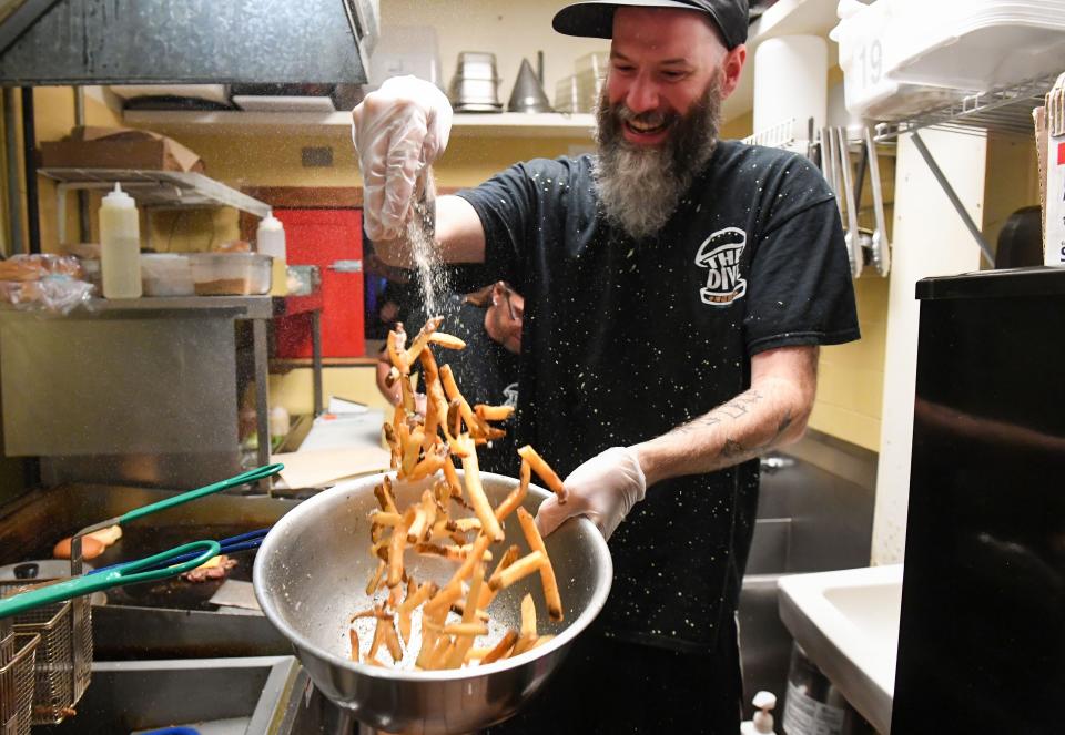 Cannon Harlan seasons a fresh batch of French fries at The Dive pop-up restaurant in the Gaslight Lounge on Wednesday, June 29, 2022, in Sioux Falls.