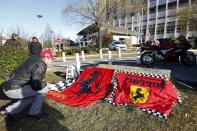 Dario, a Ferrari local fan, displays flags in front of the entrance of the emergency services at the CHU Nord hospital in Grenoble, French Alps, where retired seven-times Formula One world champion Michael Schumacher is hospitalized after a ski accident, December 30, 2013. Former Formula One champion Michael Schumacher was battling for his life in hospital on Monday after a ski injury, doctors said, adding it was too early to say whether he would pull through. Schumacher was admitted to hospital on Sunday suffering head injuries in an off-piste skiing accident in the French Alps resort of Meribel. REUTERS/Charles Platiau (FRANCE - Tags: SPORT MOTORSPORT HEALTH)