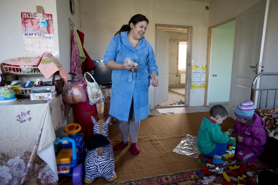 In this photo taken Thursday, March 27, 2014 Crimea's Tatar Liliya Resulova, 24, smiles as her son, Emir, 2, center, plays with Diana Setumirova, 4, right, inside of their building at recent squatter settlement in Lozovoye-2 not far from Simferopol, Crimea. On Saturday the Crimean Tatar Qurultay, a religious congress will determine whether the Tatars will accept Russian citizenship and the political system that comes with it, or remain Ukrainian citizens on Russian soil. (AP Photo/Pavel Golovkin)