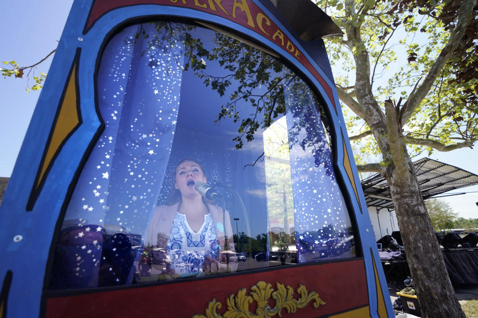 FILE - In this March 29, 2021, file photo, Opera singer Nicole Heinen sings from inside a booth sponsored by the New Orleans Opera, as part of the entertainment at "Vaccine Fest," a 24-hour COVID-19 mass vaccination event in Metairie, La., just outside New Orleans, hosted by Ochsner Health System and the Jefferson Parish Government. Louisiana is making a full-court press to get shots in arms, with sometimes creative outreach to make it as easy as possible to get vaccinated. (AP Photo/Gerald Herbert, File)