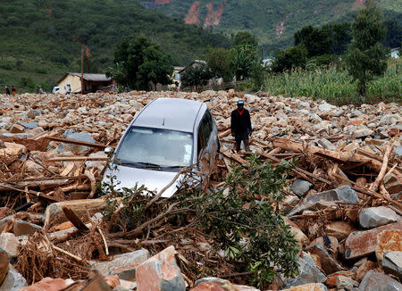 A woman stands besides a car that was swept away with debris by Cyclone Idai in Chimanimani, Zimbabwe, March 23,2019. REUTERS/Philimon Bulawayo